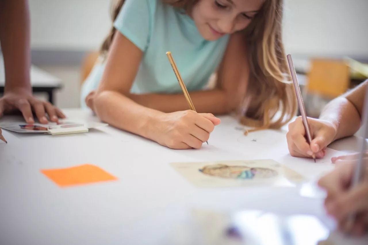 Tipos de avaliação escolar: aluna de ensino fundamental anos finais fazendo um trabalho, escrevendo em uma folha.